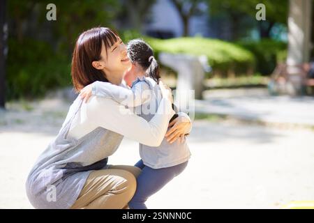 Donna sorridente che abbraccia un bambino Foto Stock