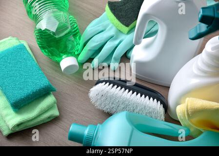 Fornitura di prodotti per la pulizia generale con vari disinfettanti e strumenti come stracci, pagliette, guanti e spazzole su un tavolo in legno. Via sopraelevata Foto Stock