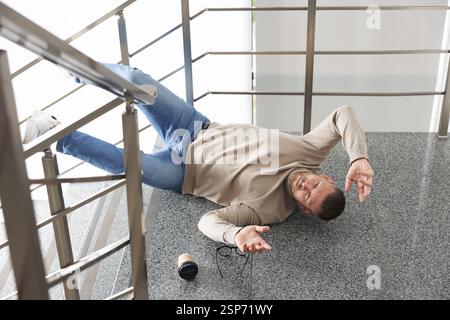 Uomo ferito sulle scale dell'edificio dopo la caduta. Incidente pericoloso Foto Stock
