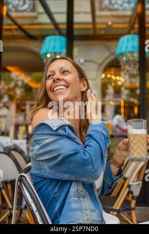 Donna sorridente che si gode un momento di caffè nel bistrot di Parigi. Foto Stock