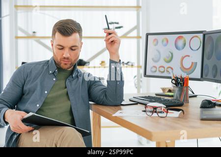 Con il tablet in mano. Progettista maschile che lavora in ufficio utilizzando un PC. Foto Stock