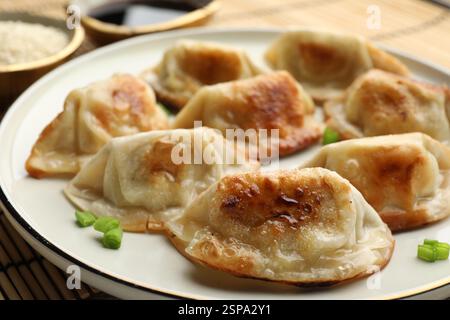 Deliziosi gyoza fritti con cipolle verdi serviti sul tavolo, primo piano Foto Stock
