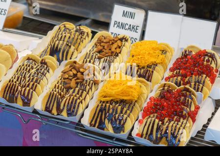 Primo piano di mini pancake conditi con salsa al cioccolato e decorati con vari condimenti, tra cui mandorle, filetti d'uovo dorati (fu Thong) e br Foto Stock