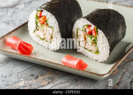 Sushirrito di pollo con riso, formaggio spalmabile, cetriolo, peperone, nori e lattuga da vicino in un piatto sul tavolo. orizzontale Foto Stock