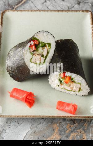 Sushirrito messicano giapponese con riso, pollo, formaggio spalmabile, verdure e lattuga da vicino in un piatto sul tavolo. Verticale Foto Stock