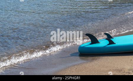 Un paddleboard in piedi poggia sul litorale mentre le dolci onde del mare vi si infrangono, creando un ambiente sereno e invitante per gli sport acquatici a Sarsala Beach, Dala Foto Stock