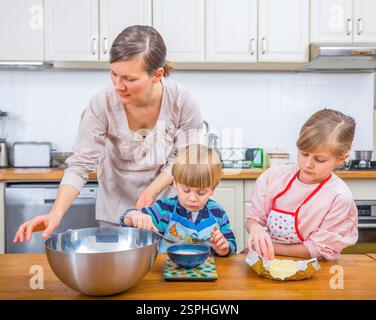 Momenti felici in famiglia come madre insegna ai suoi figli la gioia di cucinare insieme. Foto Stock