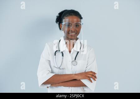 Nei dispositivi di protezione. La giovane donna afroamericana è su sfondo bianco. Foto Stock
