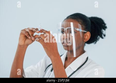Siringa di contenimento. La giovane donna afroamericana è su sfondo bianco. Foto Stock
