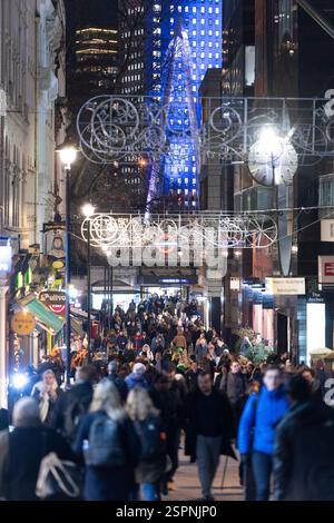 Folle di notte a Londra, vicino alla stazione Embankment, che si gode le decorazioni natalizie. La gente cammina. Foto Stock