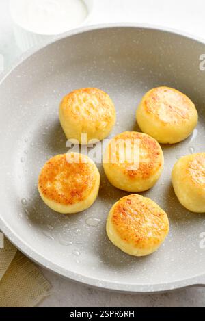 Vista ravvicinata delle frittelle di formaggio (sciroppi o frittelle di cagliata) in padella su sfondo bianco. Foto Stock
