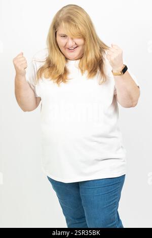 Ritratto di una donna bionda che alza i pugni in una festa gioiosa. Foto Stock