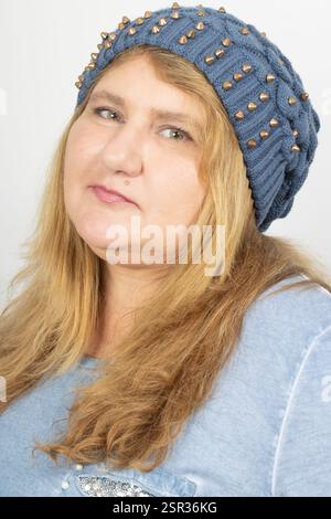 Primo piano di una donna adulta con capelli biondi e occhi verdi, con un berretto blu. Foto Stock