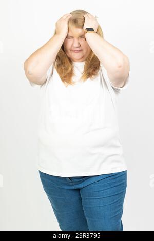 Ritratto di una donna adulta che tiene la testa con entrambe le mani, mostrando segni di angoscia e dolore. Foto Stock