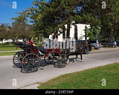 Niagara on the Lake, Canada / Una pittoresca scena di strada con i turisti che si godono un giro in carrozza trainata da cavalli in questo bellissimo villaggio storico. TH Foto Stock