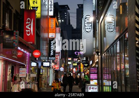 Segno di Myeongdong. Caratteri coreani, parole inglesi. Luci al neon, strada trafficata. Popolare area commerciale a Seoul, Corea del Sud. Gente che cammina, negozi, resta Foto Stock