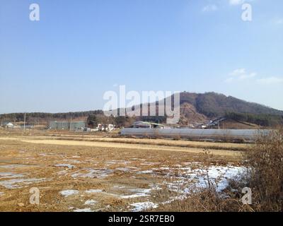 Orizzontale. Colline ondulate sotto un cielo blu limpido. Un campo con macchie di neve in primo piano. La vastità e l'apertura della scena suscitano un senso Foto Stock