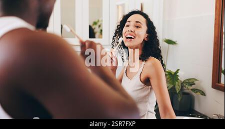 Coppia, lavarsi i denti e cantare nel bagno di casa per la routine mattutina, l'igiene orale o la relazione. Persone, benessere e cure dentistiche con Foto Stock