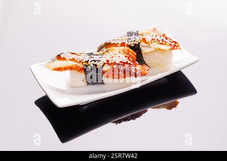 Sushi splendidamente disposto su piatto, con ingredienti freschi e colori vivaci, su uno sfondo pulito Foto Stock