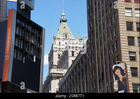 Una donna con un abito nero si trova di fronte a un imponente grattacielo nel quartiere di Manhattan a New York. Il vivace quartiere finanziario su Foto Stock
