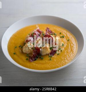 Crema di zucca autunnale con cavolfiore arrosto e prosciutto iberico. Foto Stock