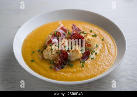 Crema di zucca autunnale con cavolfiore arrosto e prosciutto iberico. Foto Stock