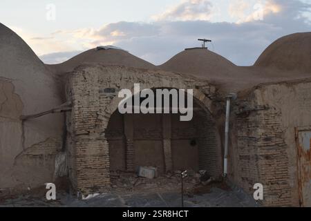 Tradizionale casa a cupola in mattoni di fango in Iran al tramonto, che mostra la storica architettura persiana del deserto con texture di terra Foto Stock