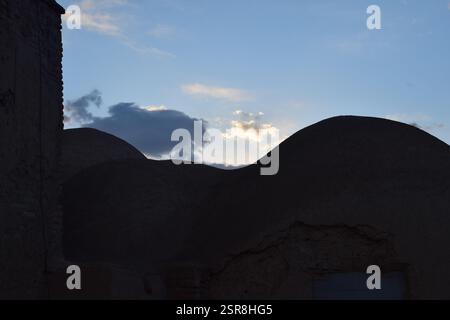 Tradizionale casa a cupola in mattoni di fango in Iran al tramonto, che mostra la storica architettura persiana del deserto con texture di terra Foto Stock