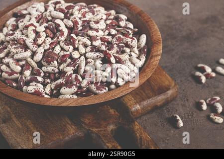Fagioli variegati, rossi con macchie bianche, crudi in una ciotola di legno, vista dall'alto, nessuna gente Foto Stock