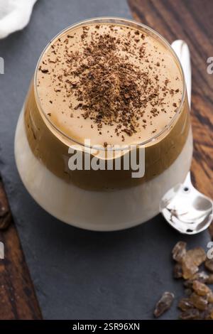 Caffè Dalgona in tazza di vetro. Bevanda coreana alla moda da caffè istantaneo, latte e zucchero di canna Foto Stock