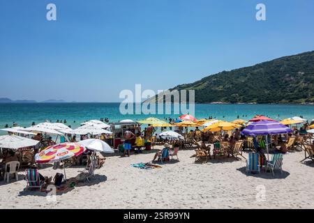 Spiaggia affollata di Prainha con turisti, ombrelloni e venditori ambulanti sulla riva con acque dell'Oceano Atlantico sotto il cielo azzurro del mattino d'estate. Foto Stock