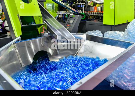 Le bottiglie in plastica blu nella linea di produzione in fase di produzione delle bottiglie in PET funzionano prima del soffiaggio delle bottiglie Foto Stock
