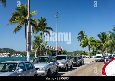 Auto parcheggiate lungo Viale Pescadores vicino al Canale Itajuru nel quartiere Centro con palme e strade acciottolate sotto il caldo cielo blu estivo pomeridiano. Foto Stock