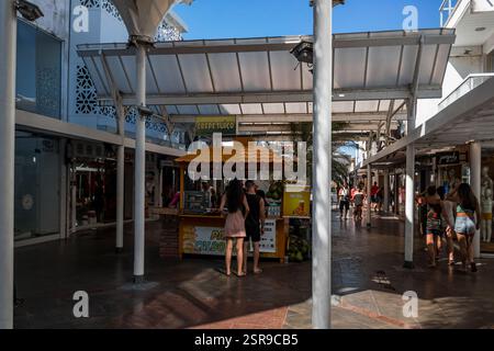 Corridoio pedonale ombreggiato all'interno del centro commerciale Rua dos Biquinis nel quartiere di Gamboa, con boutique, bancarelle alimentari e visitatori nel tardo pomeriggio. Foto Stock