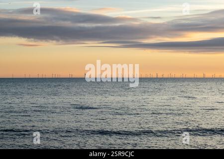 Affacciato sull'oceano dalla spiaggia di Brighton, con un parco eolico offshore all'orizzonte e un cielo al tramonto Foto Stock