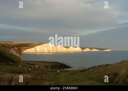 Le iconiche scogliere bianche delle sette Sorelle, in Inghilterra, inondate di luce dorata. Paesaggio costiero al tramonto. Foto Stock