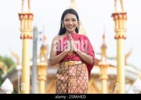 Una signora thailandese fa un tipico saluto Wai mentre si trova di fronte a un tempio buddista Foto Stock
