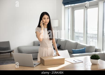 Giovane donna asiatica che ordina servizi di trasporto espresso tramite telefonata Foto Stock