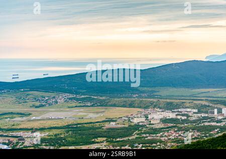 La prospettiva aerea cattura Gelendzhik, russia al crepuscolo. Affacciata sul verde lussureggiante, sul mare sereno e sulle montagne lontane, la scena mostra una luce calda e soffusa Foto Stock