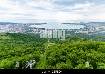 La splendida prospettiva aerea di Gelendzhik mostra una vegetazione lussureggiante, un mare blu tranquillo e un'affollata cittadina costiera. Le funivie scivolano sulle colline verdeggianti durante la guerra Foto Stock