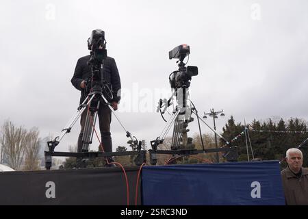 cameraman con la sua videocamera che gira all'aperto nel parco cittadino Foto Stock