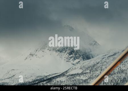 Montagna innevata coperta di nuvole nelle Alpi Lyngen, inverno della Norvegia settentrionale Foto Stock