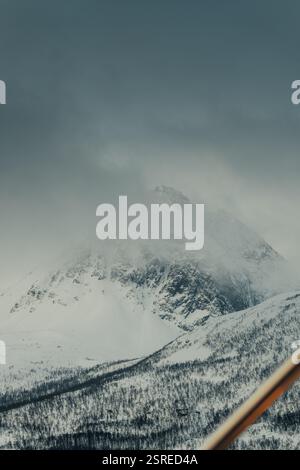 Montagna invernale innevata ricoperta di nuvole nelle Alpi Lyngen, Norvegia settentrionale Foto Stock