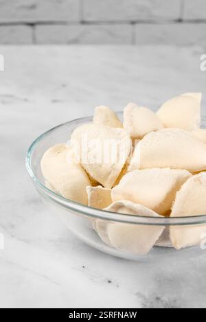 Una ciotola di gnocchi congelati su sfondo chiaro. Impasti semilavorati congelati Foto Stock