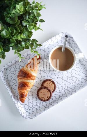 Deliziosi croissant per la colazione, biscotti e una tazza di caffè sul tavolo. Foto Stock