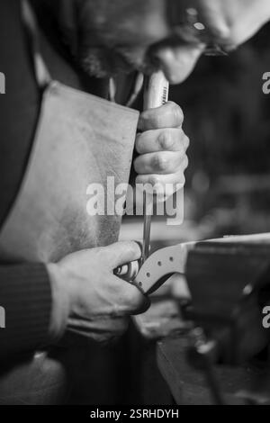 Un artigiano esperto che utilizza uno scalpello su un rotolo di violino, fuoco intenso in monocromia Foto Stock