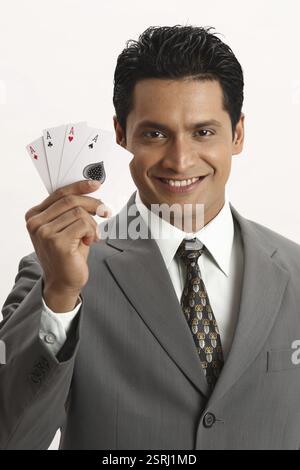 Imprenditore azienda quattro assi di carte da gioco nel suo pollice e il dito indice della mano destra il signor#703T Foto Stock
