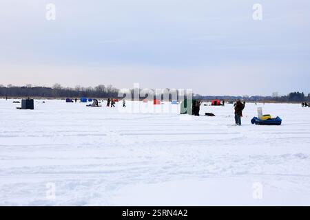 Grecia, NY, Stati Uniti - 25 gennaio 2025 - pescatori di ghiaccio che pescano attraverso il ghiaccio nella parte settentrionale dello stato di New York. Rifugi per la pesca sul ghiaccio sparsi attraverso la baia ghiacciata Foto Stock