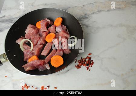 Pezzi di maiale crudo, carne di manzo marinata con condimento e verdure, cipolle in un piatto. Foto Stock