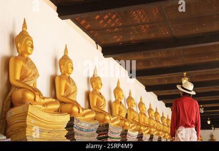 Visitatore al Chiostro con le file di immagini dorate del Buddha seduto nel Tempio buddista Wat Phutthaisawan, Ayutthaya, Thailandia Foto Stock